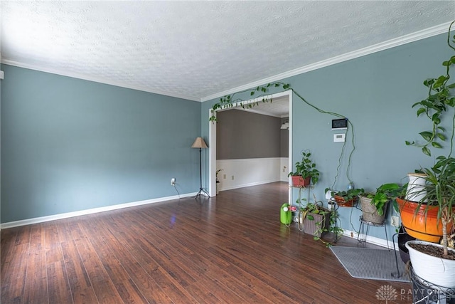 empty room featuring a textured ceiling, dark hardwood / wood-style floors, and ornamental molding