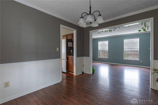 unfurnished dining area with a textured ceiling, dark hardwood / wood-style flooring, crown molding, and a notable chandelier