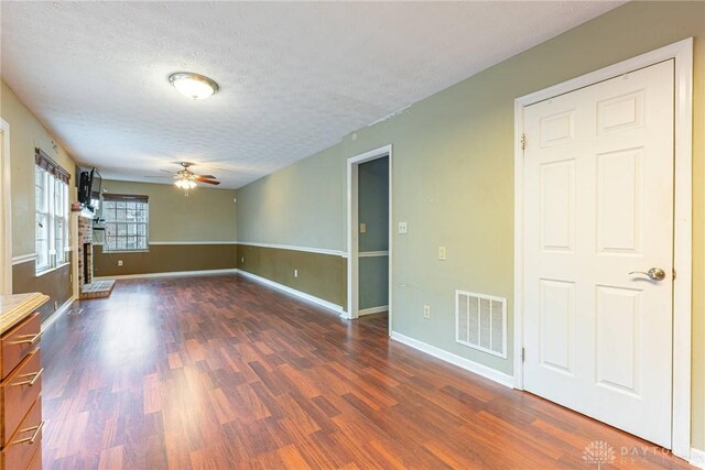 unfurnished living room featuring a textured ceiling, dark hardwood / wood-style floors, and ceiling fan