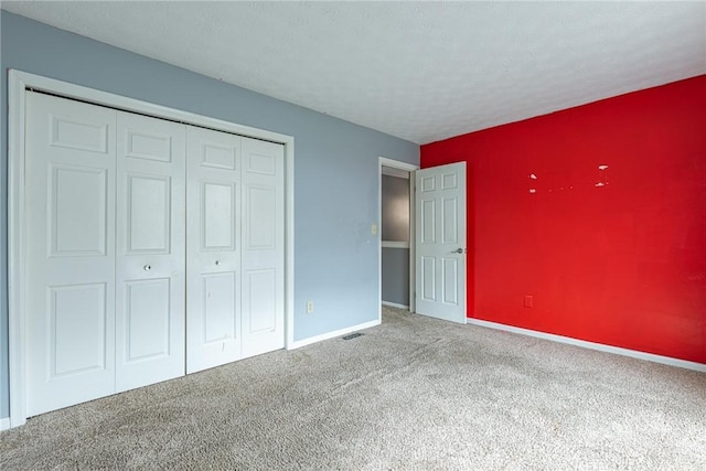 unfurnished bedroom with carpet, a closet, a textured ceiling, and baseboards