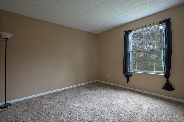 unfurnished room featuring a textured ceiling, baseboards, and carpet flooring