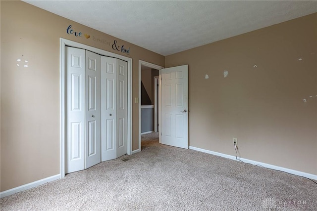 unfurnished bedroom with a textured ceiling, a closet, carpet flooring, and baseboards