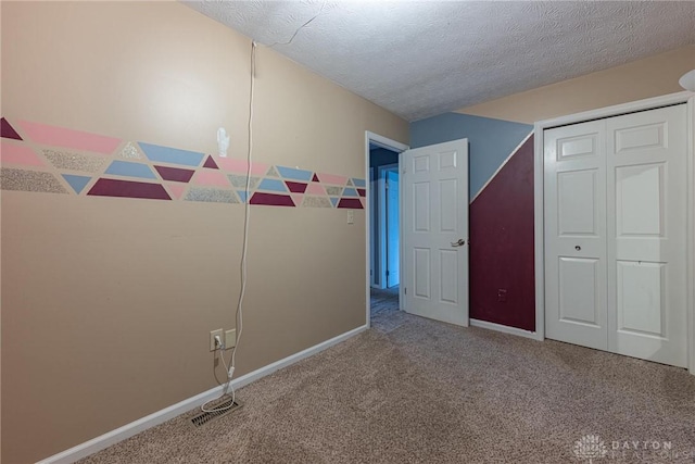 unfurnished bedroom with carpet, a closet, a textured ceiling, and baseboards