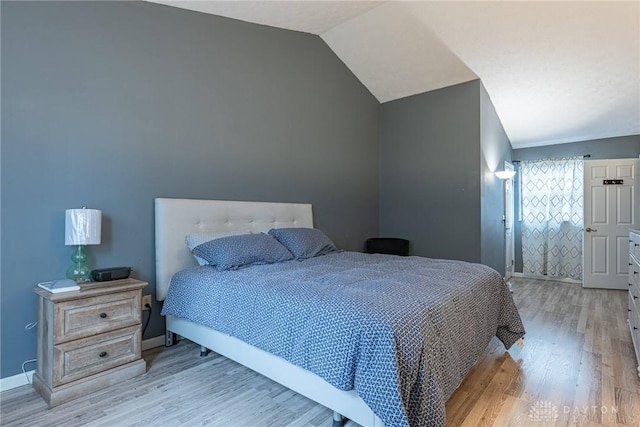 bedroom featuring light wood-style floors, baseboards, and vaulted ceiling