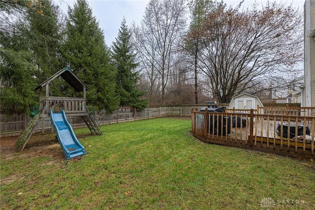 view of yard with a playground, a deck, and a storage unit