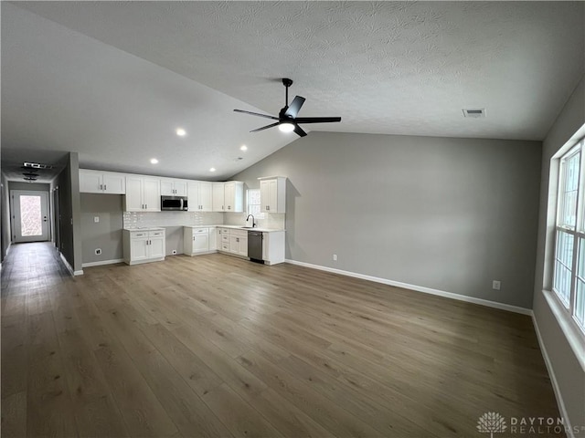 unfurnished living room featuring ceiling fan, hardwood / wood-style flooring, sink, and lofted ceiling