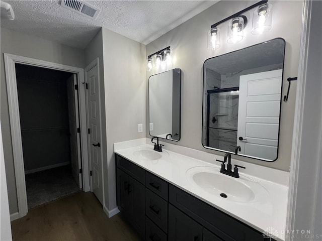 bathroom featuring vanity, a shower with shower door, a textured ceiling, and wood-type flooring