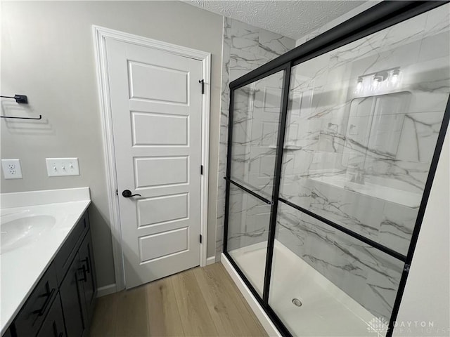 bathroom with vanity, hardwood / wood-style floors, a textured ceiling, and an enclosed shower