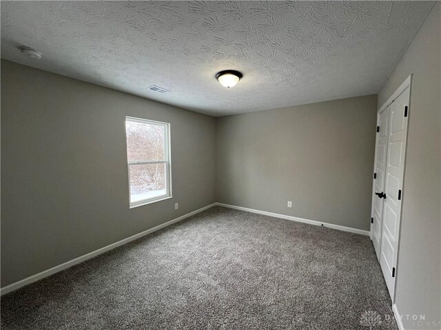 empty room featuring a textured ceiling and carpet flooring