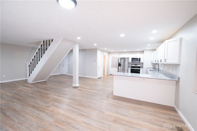 kitchen featuring white cabinetry, light stone counters, light hardwood / wood-style flooring, kitchen peninsula, and appliances with stainless steel finishes