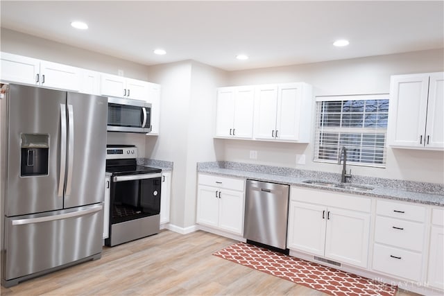 kitchen with white cabinets, light hardwood / wood-style floors, sink, and appliances with stainless steel finishes