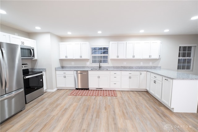 kitchen with white cabinets, sink, light hardwood / wood-style flooring, kitchen peninsula, and stainless steel appliances