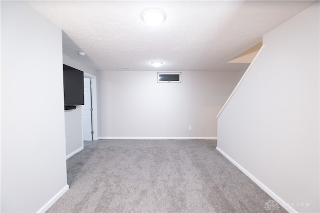 basement featuring light carpet and a textured ceiling