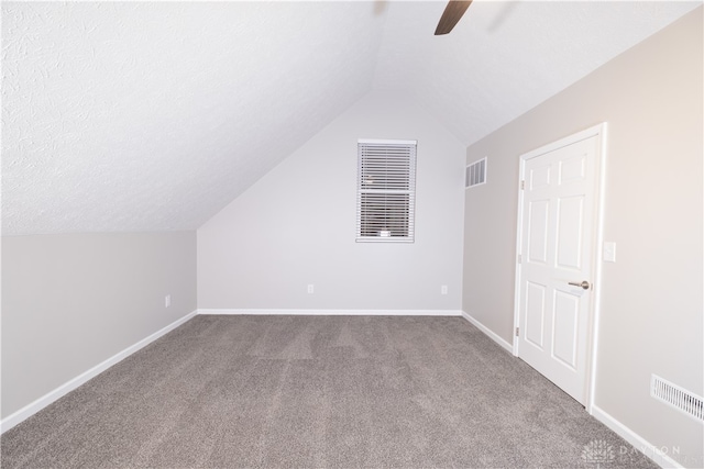 bonus room featuring carpet flooring, a textured ceiling, vaulted ceiling, and ceiling fan