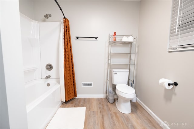 bathroom featuring hardwood / wood-style flooring, toilet, and shower / bathtub combination with curtain