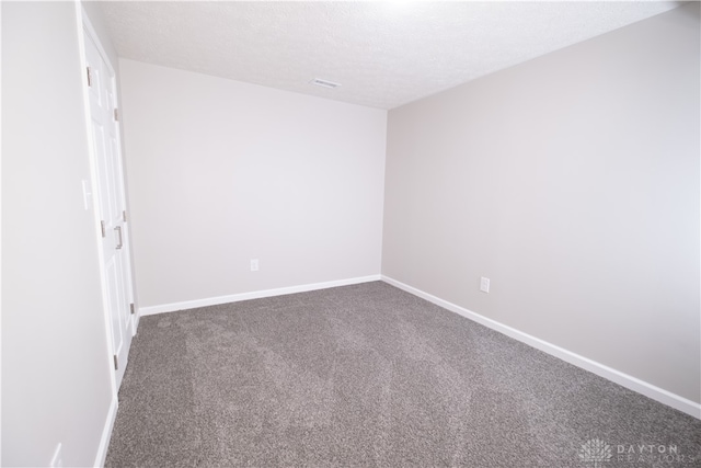 empty room with a textured ceiling and dark carpet