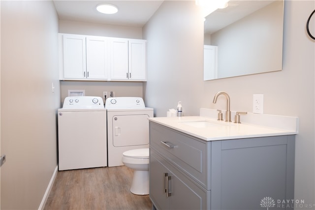 bathroom with toilet, vanity, wood-type flooring, and independent washer and dryer