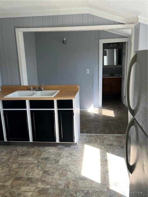 kitchen with ornamental molding, lofted ceiling, sink, and fridge