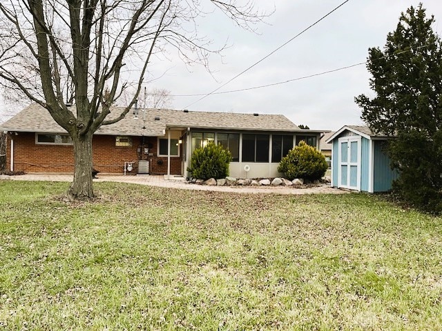 rear view of house featuring a sunroom, a storage shed, and a lawn