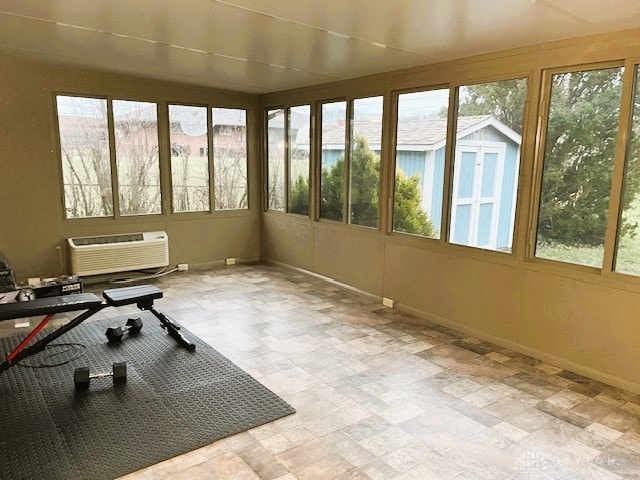 sunroom featuring a healthy amount of sunlight and a wall unit AC