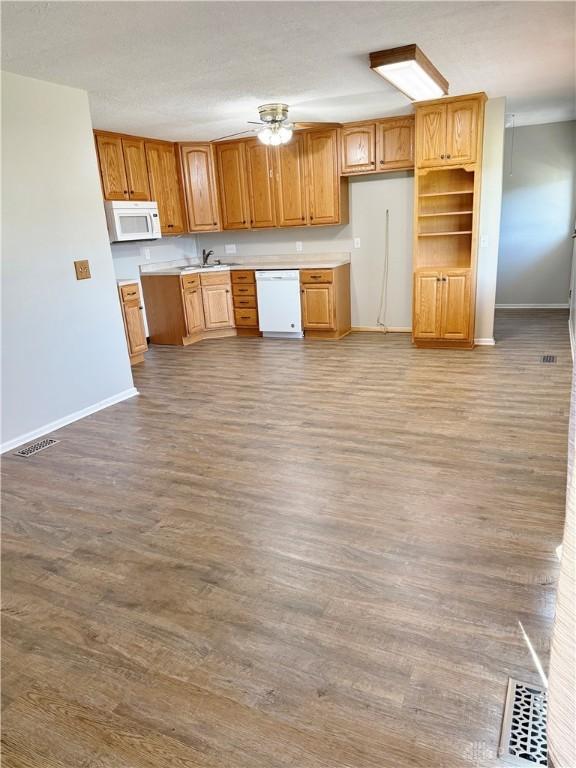 kitchen with wood-type flooring, white appliances, ceiling fan, and sink