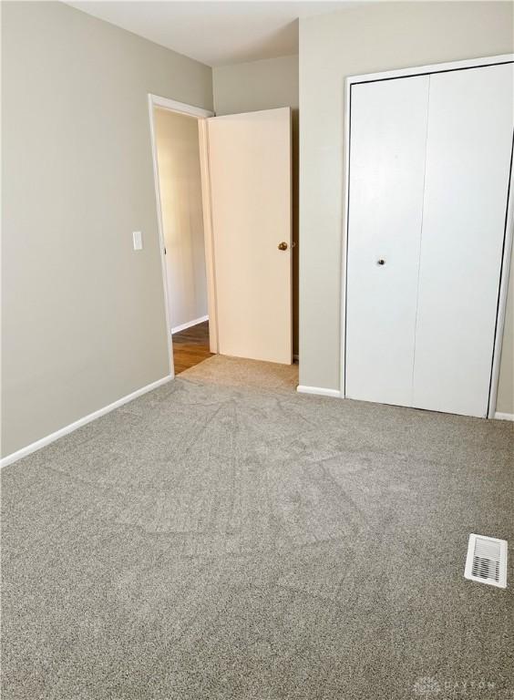 unfurnished bedroom featuring a closet and light colored carpet