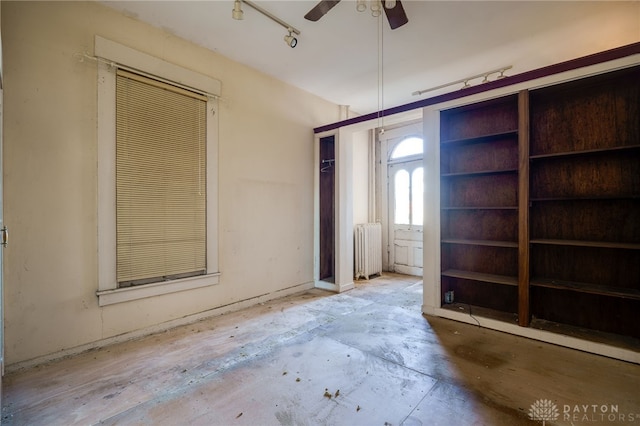 unfurnished room featuring radiator, ceiling fan, and track lighting