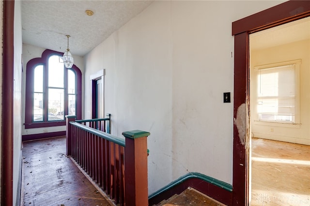 corridor featuring a textured ceiling and a notable chandelier