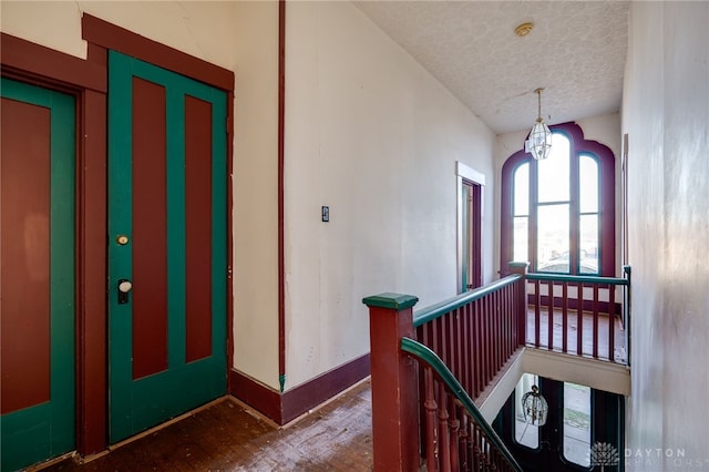 hallway featuring a textured ceiling, hardwood / wood-style flooring, and a notable chandelier