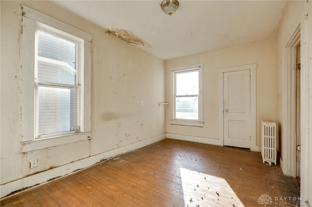 unfurnished room featuring radiator heating unit and hardwood / wood-style floors