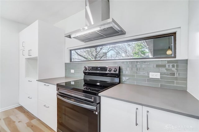 kitchen with black electric range, wall chimney exhaust hood, white cabinetry, and decorative backsplash