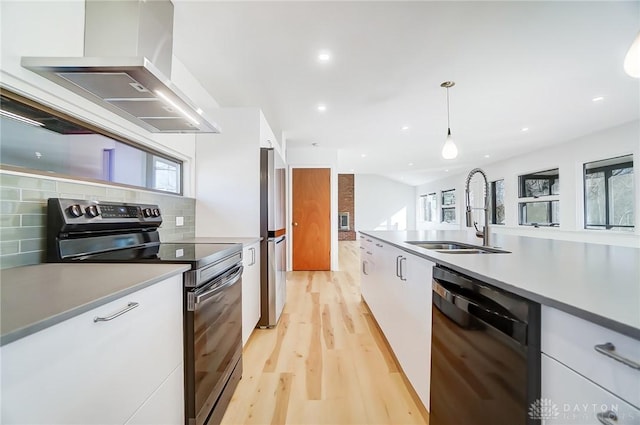 kitchen featuring wall chimney range hood, light wood-style flooring, white cabinetry, black appliances, and a sink