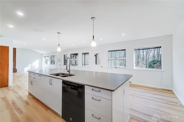 kitchen with a sink, open floor plan, light wood finished floors, and dishwasher