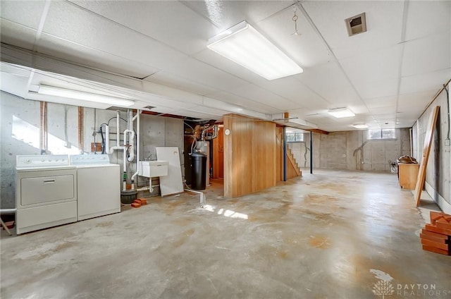 basement featuring water heater, washer and clothes dryer, and a sink