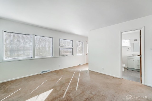 interior space with a sink, visible vents, baseboards, and light carpet