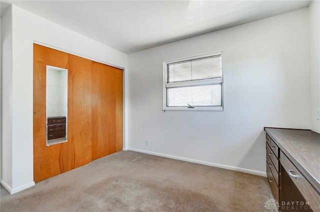 unfurnished bedroom featuring a closet, baseboards, and light carpet