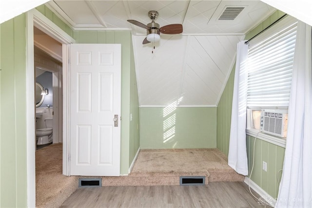 bonus room with wood walls, ceiling fan, light colored carpet, and vaulted ceiling