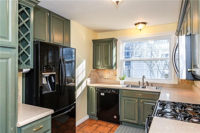 kitchen featuring backsplash, green cabinets, sink, and black appliances