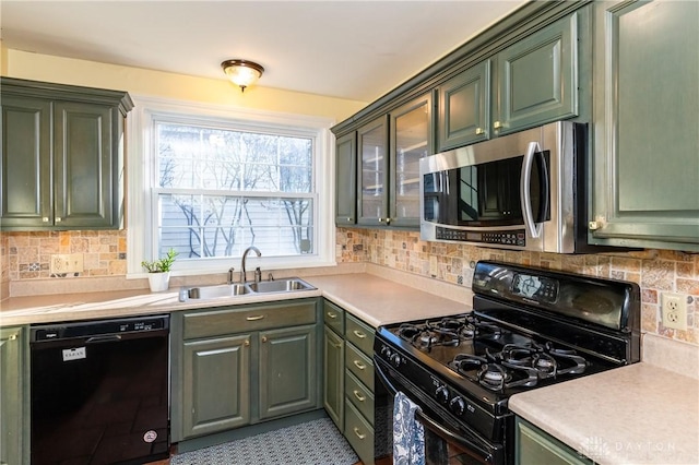 kitchen with black appliances, backsplash, sink, and green cabinetry