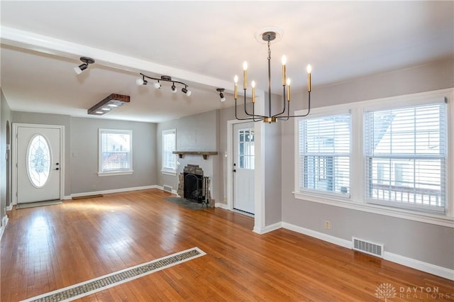 foyer entrance with a fireplace, light hardwood / wood-style flooring, a wealth of natural light, and a notable chandelier