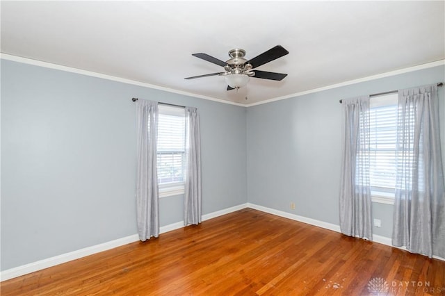 empty room featuring a wealth of natural light, hardwood / wood-style floors, ceiling fan, and crown molding