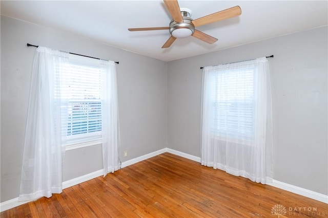 empty room featuring a wealth of natural light, hardwood / wood-style floors, and ceiling fan