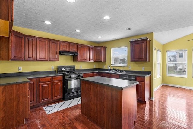 kitchen with dark hardwood / wood-style flooring, a center island, black appliances, and vaulted ceiling