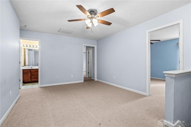 unfurnished bedroom featuring ceiling fan, ensuite bathroom, and light carpet