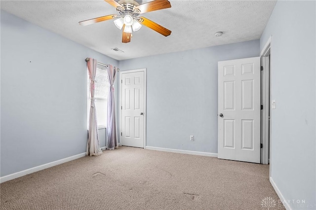 carpeted spare room featuring ceiling fan and a textured ceiling