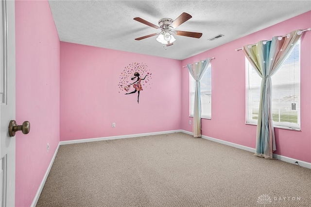 spare room with a textured ceiling, carpet floors, and ceiling fan