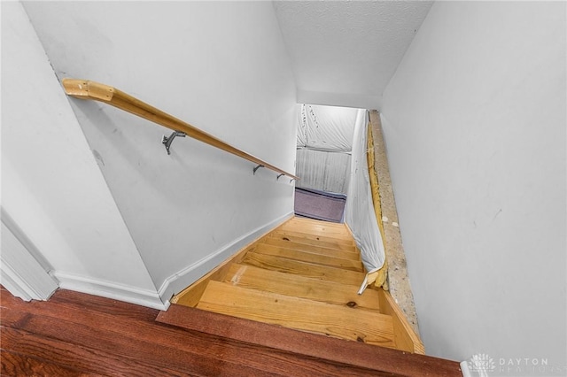 staircase with wood-type flooring and a textured ceiling