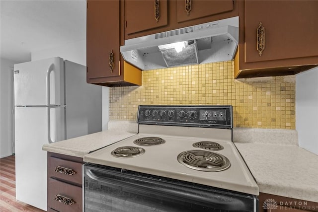 kitchen with light wood-type flooring, white appliances, and tasteful backsplash