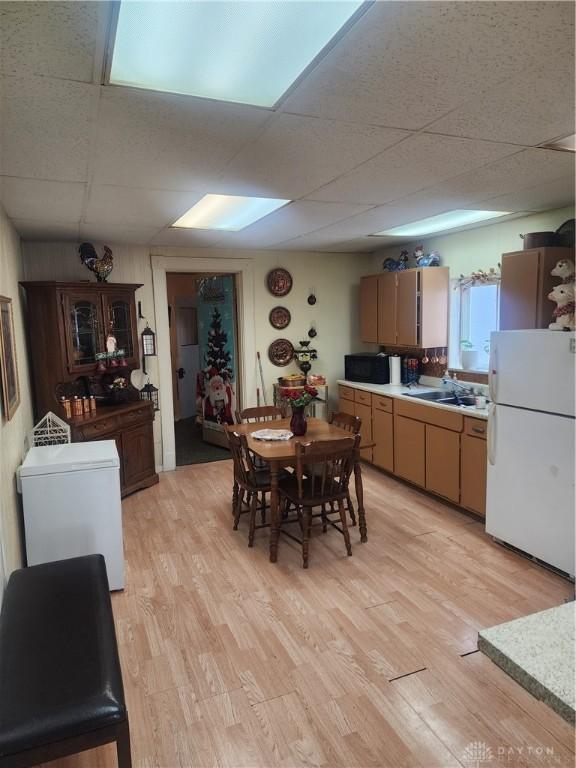 dining area with a drop ceiling, light wood-type flooring, and sink