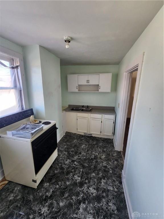 kitchen with white range with electric cooktop, white cabinetry, and sink